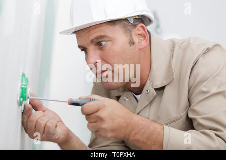 male electrician working on plug socket Stock Photo