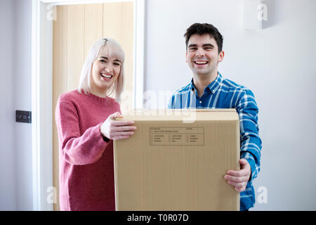 Portrait Of Young Couple Carrying Boxes Into New Home On Moving Day