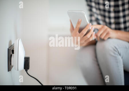 Woman Controlling Smart Plug Using App On Mobile Phone Stock Photo