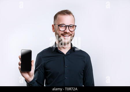 Portrait of happy man in glasses demonstrating blank smartphone with smile. Copyspace for yor app Stock Photo
