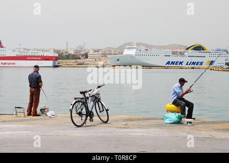 Two male anglers fishing at Piraeus port in Athens, Greece on May 11, 2016. Piraeus is the largest passenger port in Europe. Stock Photo