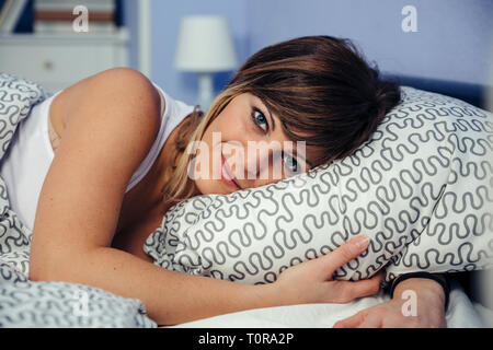 Young woman lying on the bed looking at camera Stock Photo