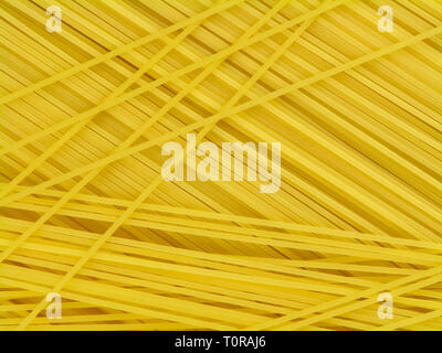 Uncooked yellow italian pasta spaghetti chaotically located top view close-up Stock Photo