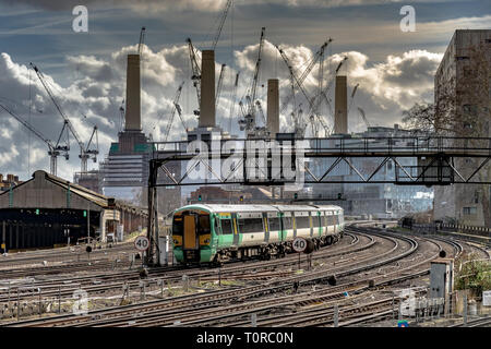 A Southern Rail train approaching Ebury Bridge on the final approach to Victoria Station ,with Battersea Power Station in the distance ,London, UK Stock Photo