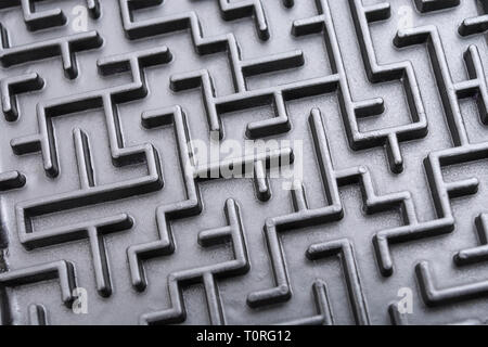 Macro shot of small toy maze painted black. For complex, getting lost, navigating, problem solving, unreachable goals, Brexit negotiations talks. Stock Photo