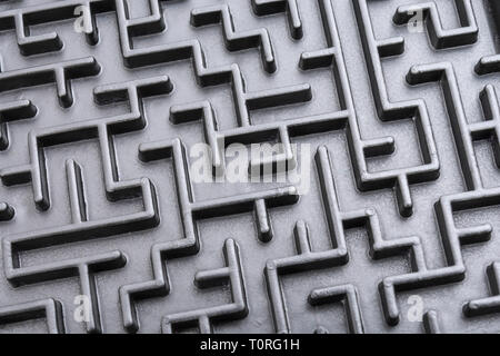 Macro shot of small toy maze painted black. For complex, getting lost, navigating, problem solving, unreachable goals, Brexit negotiations talks. Stock Photo