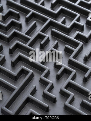 Macro shot of small toy maze painted black. For complex, getting lost, navigating, problem solving, unreachable goals, Brexit negotiations talks. Stock Photo