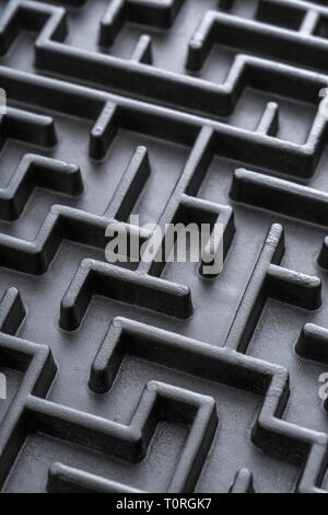 Macro shot of small toy maze painted black. For complex, getting lost, navigating, problem solving, unreachable goals, Brexit negotiations talks. Stock Photo