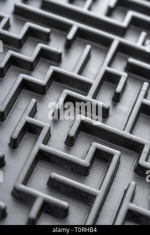 Macro shot of small toy maze painted black. For complex, getting lost, navigating, problem solving, unreachable goals, Brexit negotiations talks. Stock Photo