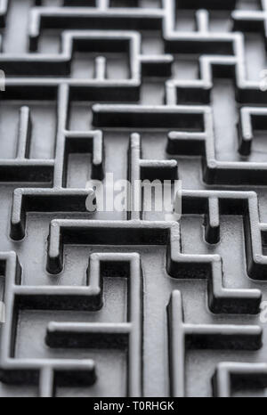 Macro shot of small toy maze painted black. For complex, getting lost, navigating, problem solving, unreachable goals, Brexit negotiations talks. Stock Photo