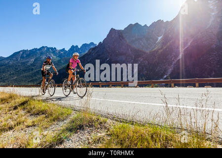 A man and woman riding bikes in the mountains. North Cascades Highway in Washington State, USA. Highway 20. Washington Pass. Stock Photo