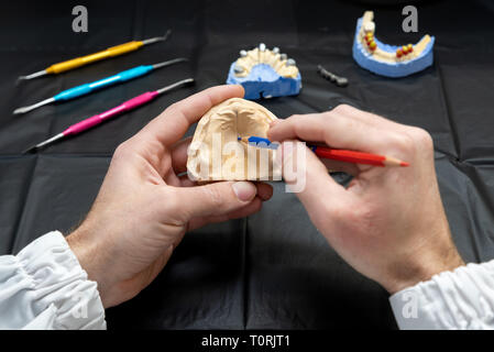 Dental technician or dentist working with tooth dentures in his laboratory Stock Photo
