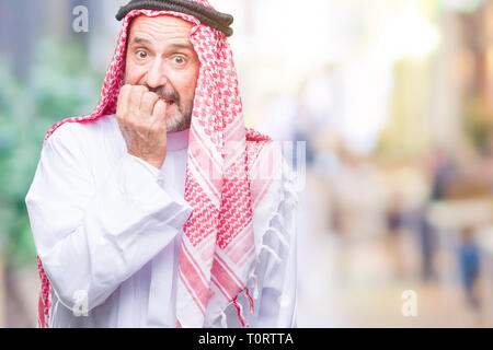 Senior arab man wearing keffiyeh over isolated background looking stressed and nervous with hands on mouth biting nails. Anxiety problem. Stock Photo