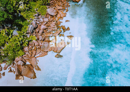 Seychelles La Digue Island. Aerial top view of ocean waves hitting huge bizarre granite rocks on the tropical beach anse cocos with turquoise azure Stock Photo