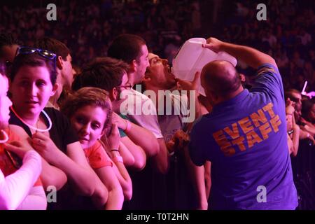 A front row concert fan is shown receiving an H2O pour from a security guard at a concert event. Stock Photo