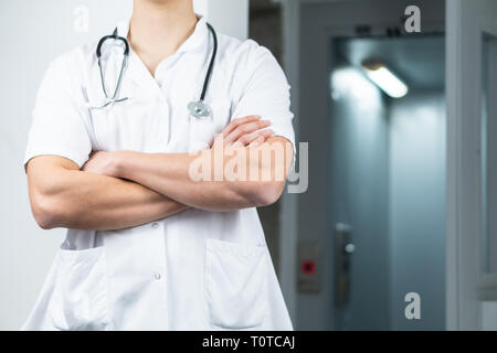 Bright portrait photo of male doctor's body in uniform with stethoscope and crossed hands, copy space Stock Photo