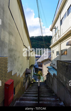 A stairwell leads down a narrow alley between old, run down homes in rural Minakami, Gunma, Japan, on an autumn afternoon. Stock Photo