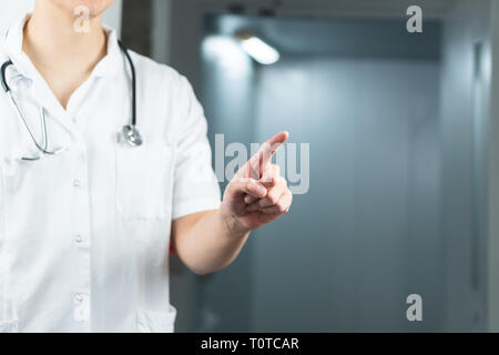 Bright close up of male doctor in uniform with stethoscope pointing finger in the air. Copy space or graphic space Stock Photo
