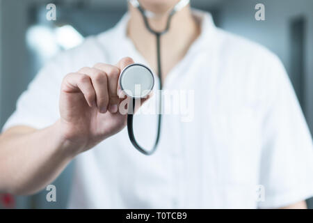 Bright close up of male doctor in uniform with stethoscope. Listening and holding stethoscope. Copy space Stock Photo