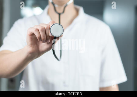 Bright close up of male doctor in uniform with stethoscope. Listening and holding stethoscope. Copy space Stock Photo