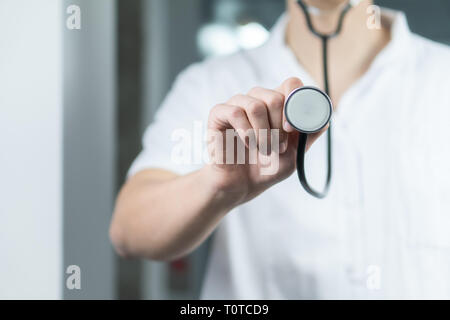 Bright close up of male doctor in uniform with stethoscope. Listening and holding stethoscope. Copy space Stock Photo