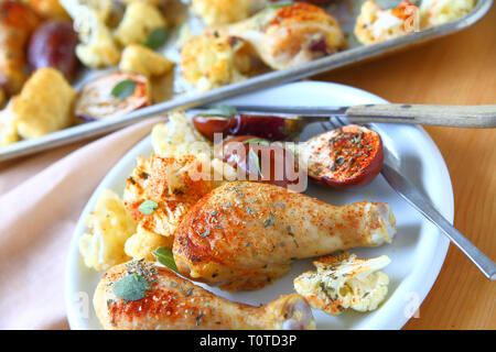 Plate of roasted chicken legs, mini eggplants and cauliflower seasoned with dried herbs and smoked paprika Stock Photo
