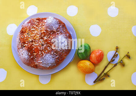 Easter bread, colored eggs and  willow catkins on a yellow tablecloth with white dots Stock Photo