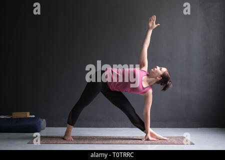 Girl standing in Utthita Trikonasana, extended triangle pose. Stock Photo