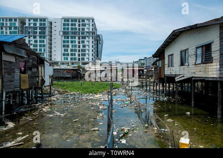 A traditional stilt house water village settlement sits in front of modern development in Kota Kinabalu, Sabah, Borneo, Malaysia. Stock Photo