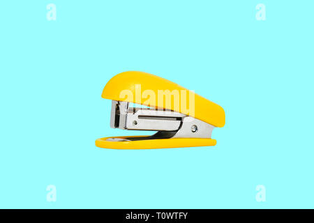 Yellow-colored stapler closeup on a blue background 2019 Stock Photo
