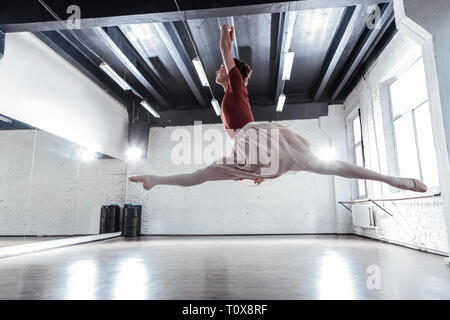Beautiful skilled ballerina doing splits in the air Stock Photo