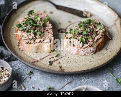 Two toasts duck with prunes rillettes pate on white bread with sprouts and various seeds on a vintage plate Stock Photo