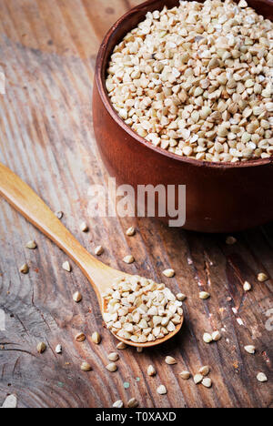 Still life  with buckwheat grain heap in wooden bowl on vintage wooden table background. Organic healthy eating cuisine. Vegan gluten free buckwheat c Stock Photo