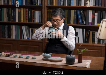 Senior businessman drinking tea in study Stock Photo