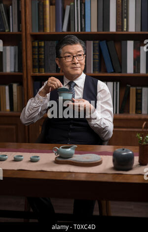 Senior businessman drinking tea in study Stock Photo