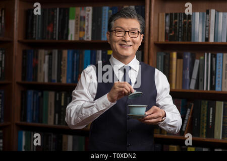 Senior businessman drinking tea in study Stock Photo
