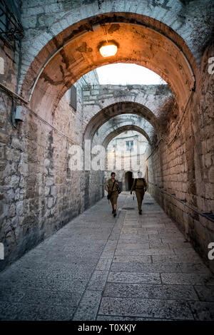 White and black women in military uniform walking in narrow street of the old city of Jerusalem. Jerusalem, Israel: 24 October, 2018. Stock Photo