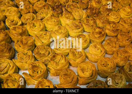 Close up of a tray with freshly baked sweet buns. Delicious and appetizing sugary treats set on bakery sheet. Confectionary store selling brownish pas Stock Photo