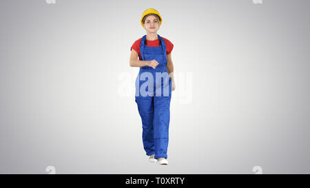 Confident experienced forewoman walking with will to work on gradient background. Stock Photo