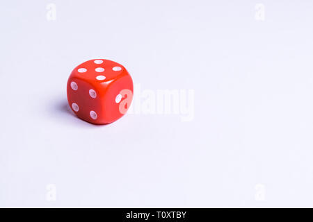 A red colored playing dice isolated on a uniform background Stock Photo