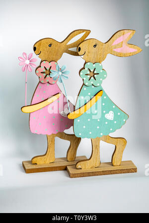 Two colorful wooden easter bunnies in front of a light background. Stock Photo
