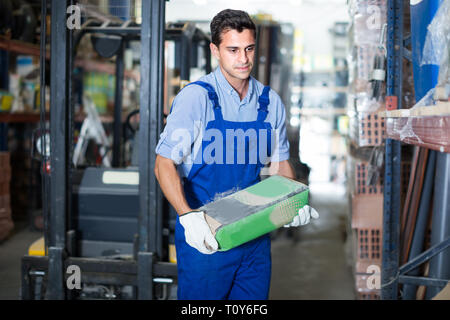 Sellerman is checking bags with cement in the building store. Stock Photo