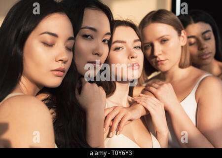 selective focus of five beautiful multicultural women posing at camera in sunlight Stock Photo