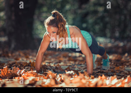 Woman doing push ups in the park. Stock Photo
