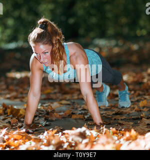 Woman doing push ups in the park. Stock Photo