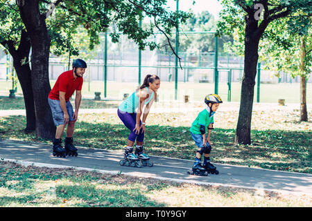 Family with one child roller skating in park. Stock Photo