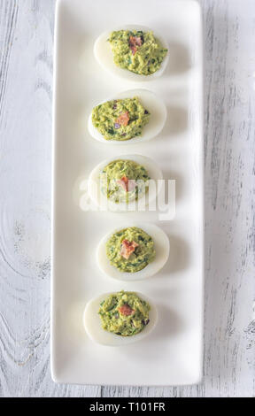Guacamole and bacon deviled eggs on the white plate Stock Photo