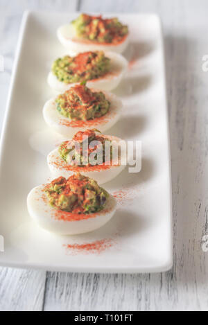 Guacamole and bacon deviled eggs on the white plate Stock Photo