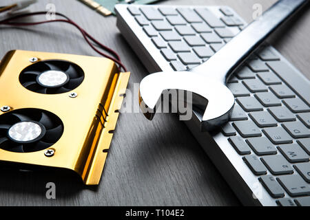 big wrench and a computer keyboard and computer parts close up Stock Photo