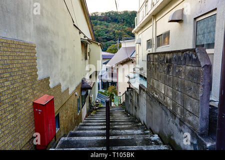 A stairwell leads down a narrow alley between old, run down homes in rural Minakami, Gunma, Japan, on an autumn afternoon. Stock Photo